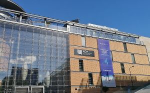 Modernes Verwaltungsgebäude in Lublin mit Glasfassade und Banner, sonniger Tag.
