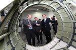 Axis-CEO Martin Rossmann mit EU-Regiojnalkommissar Johannes Hahn und Landesrat Christian Buchmann in der Produktion höchstrealistischer Voll-Flugsimulatoren (v.l.n.r.)